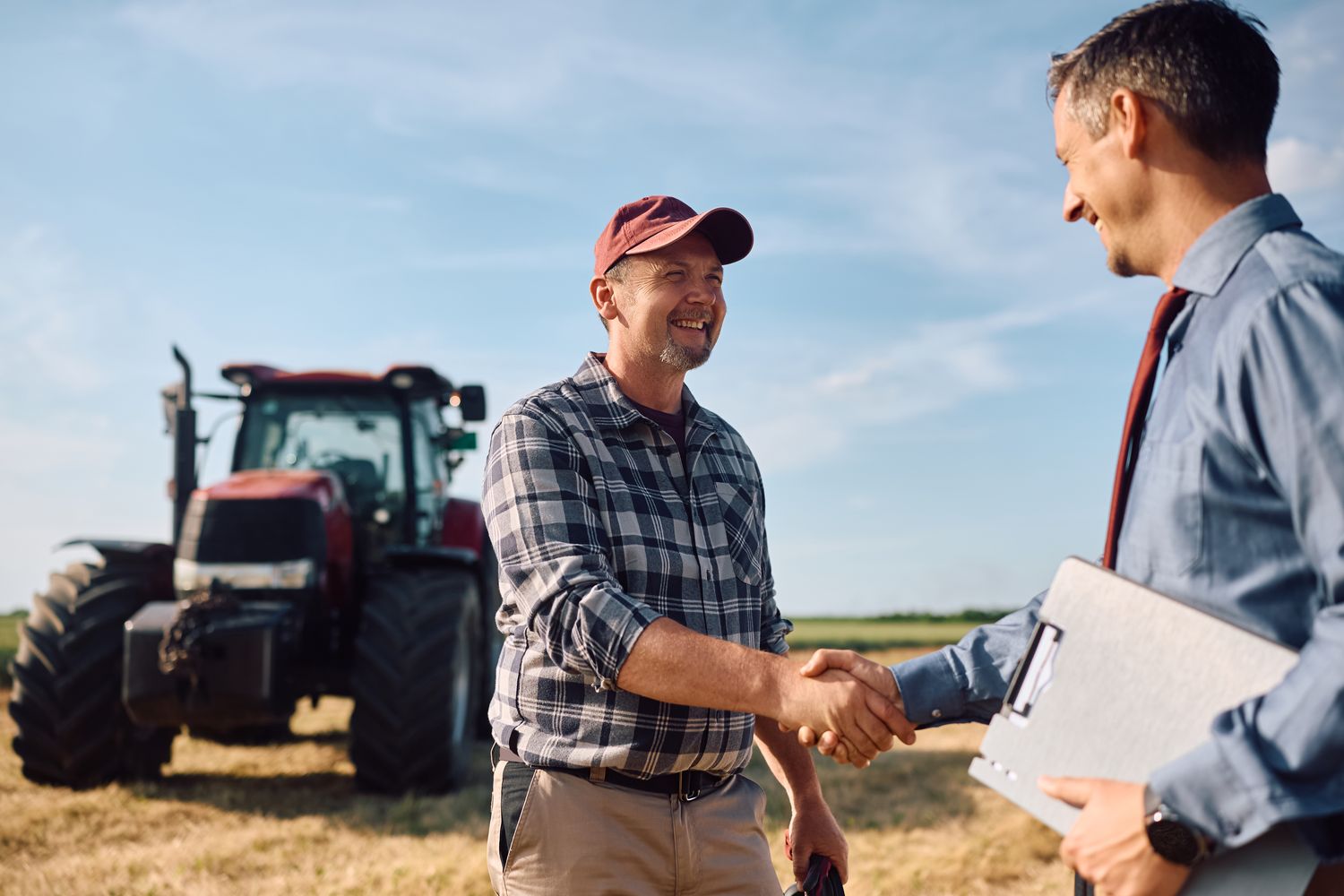 Insurance adviser greeting a Waikato farm owner beside a tractor